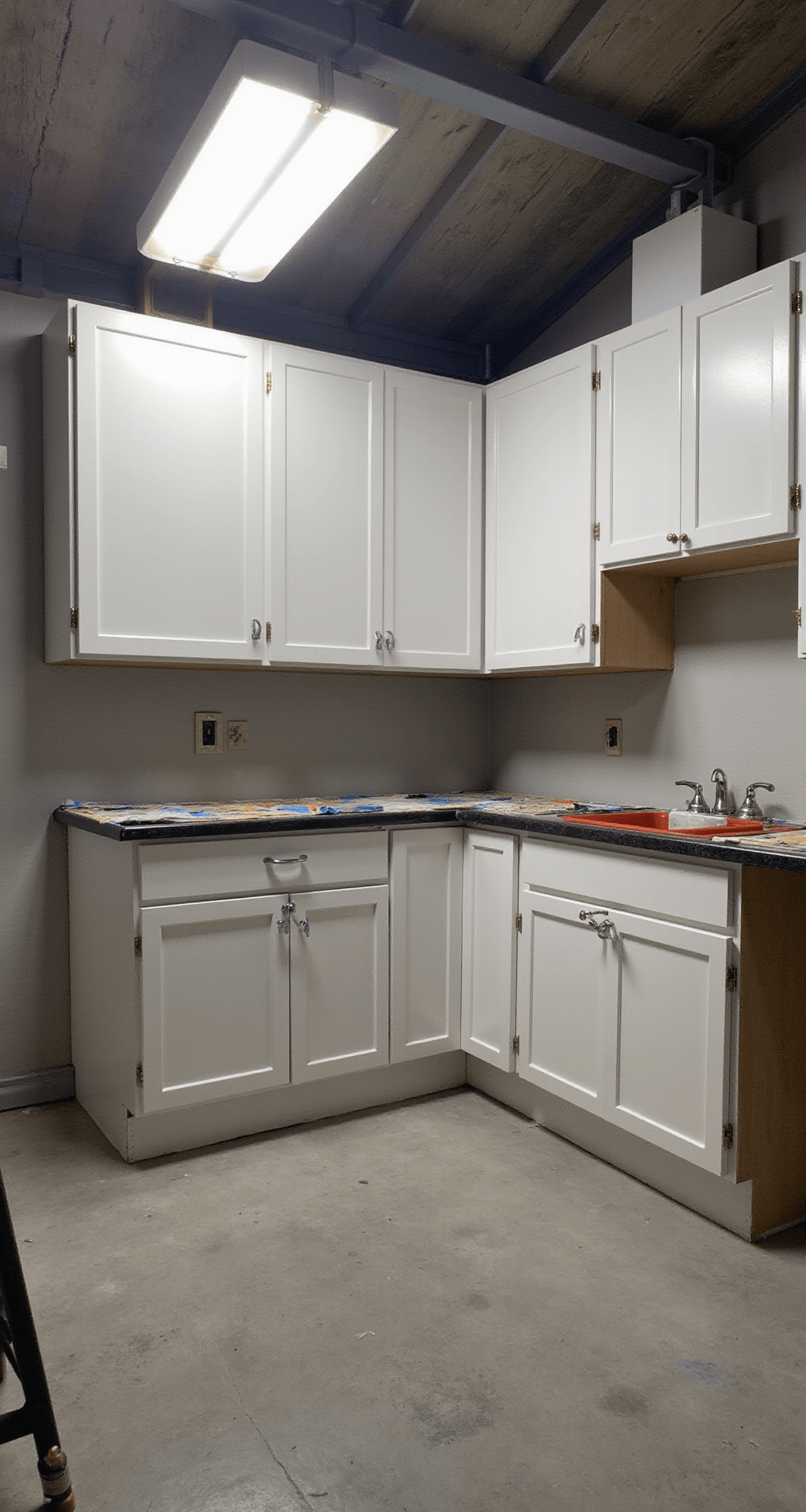 Transforming Your Kitchen: The Ultimate Guide to Painting Kitchen Cabinets Professional painter's workspace in a 16x18ft kitchen, featuring drop cloths for surface protection, organized tools on a workbench, labeled cabinet doors, and bright overhead lights illuminating a systematic and clean setup.